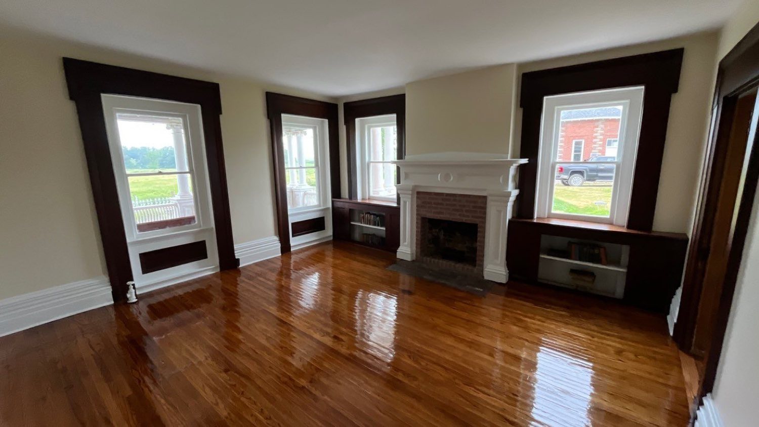 Restored parlor with original dark trim, a fireplace mantel, and refinished hardwood floors