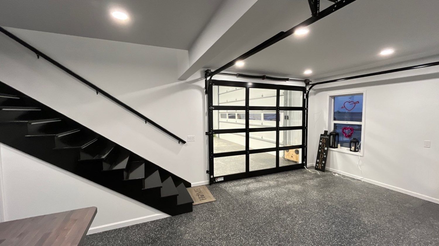 Open black steel stair and glass overhead doors in a finished barndominium build