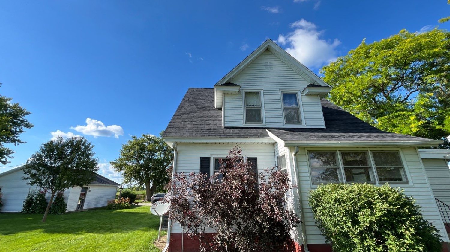 Two-story white farmhouse in Aledo, Illinois with a completed dark architectural shingle roof