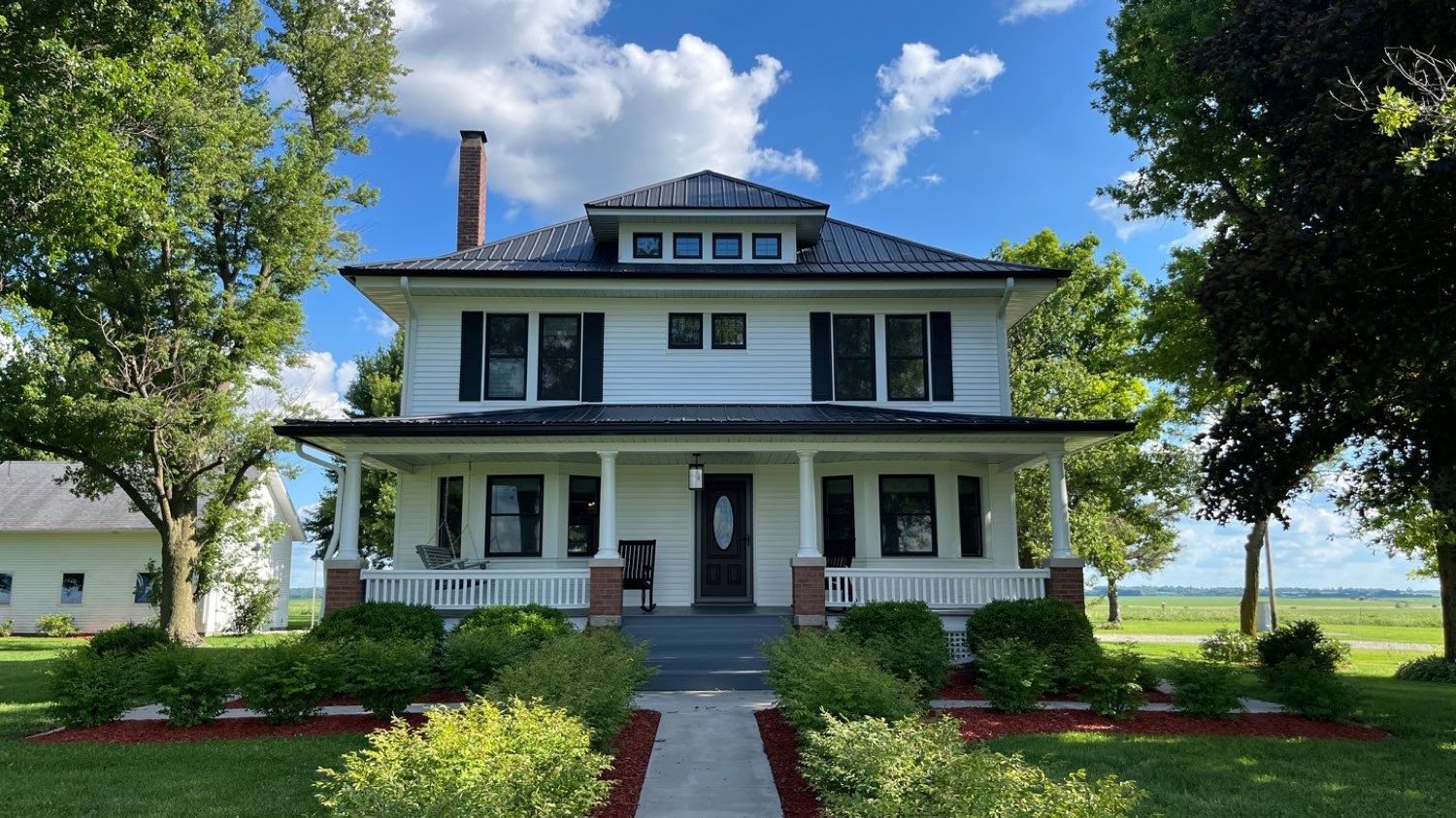 Restored Foursquare farmhouse against a bright blue sky